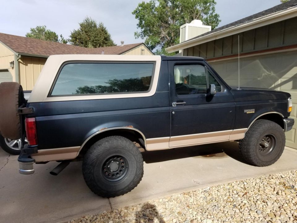 Side view of a 1994 Ford Bronco with a dark blue body and tan top
