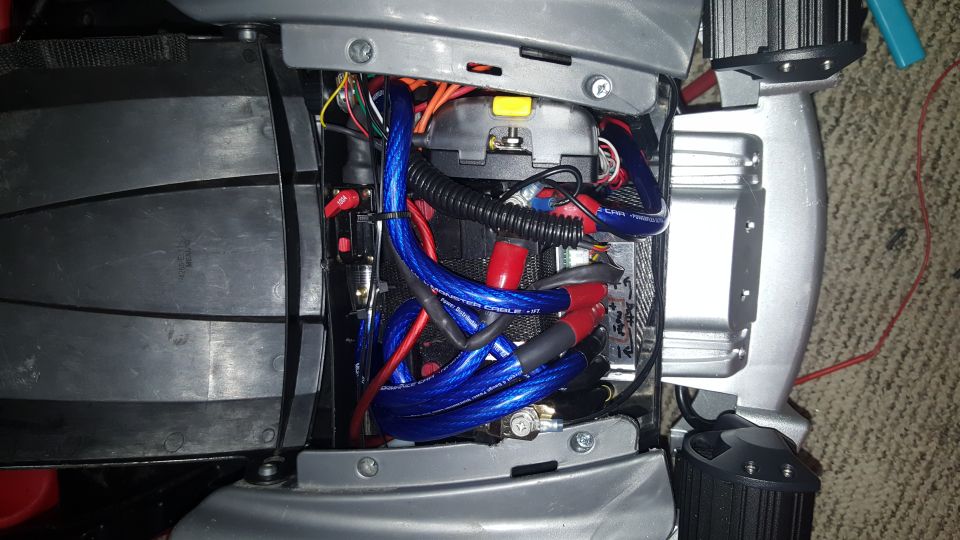 Close-up of car audio amplifier wiring with blue and red cables, fuse holder, and black protective conduit