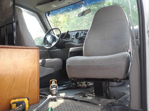 1999 Ford E250 - The interior of a van shows the driver's area with seats and dashboard, along with tools on the floor.