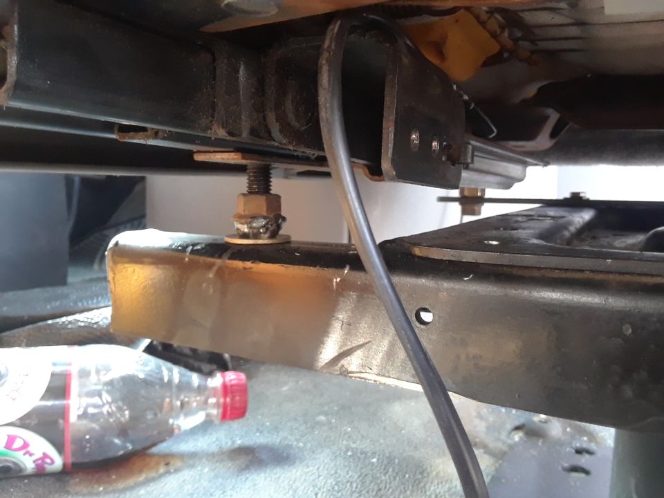 Seat mounting hardware with a bolt and nut, next to a plastic bottle with a red cap
