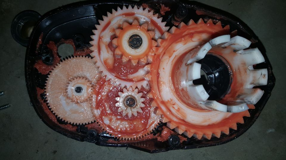Close-up of a gearbox with red grease and plastic gears.