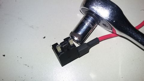 2000 Pontiac Grand Prix - A close-up shot shows a socket wrench attached to a fuse tap with a red wire. The fuse tap is a black plastic component with two metal pron…