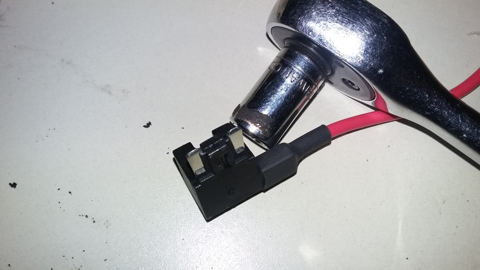 Socket wrench on a fuse tap with a red wire.