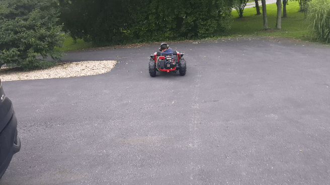 Person on red ATV on asphalt driveway