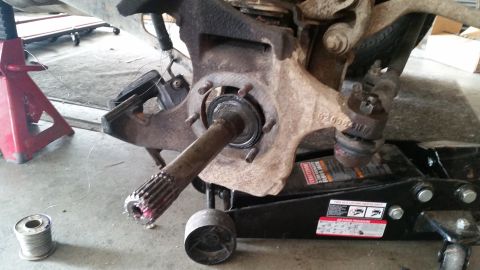 1985 Ford Bronco - A close-up view of a vehicle's front suspension and hub assembly, with a drive axle protruding from the knuckle. The vehicle is supported b…