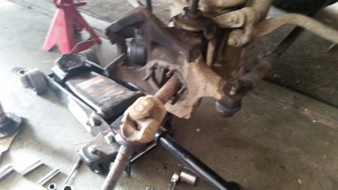 1985 Ford Bronco - A hydraulic floor jack is positioned under a vehicle's suspension components, which appear to be undergoing maintenance or repair. Various…