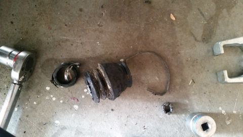 1985 Ford Bronco - A disassembled ball joint and a ratchet are laid out on a concrete surface. The ball joint appears to be worn and damaged.