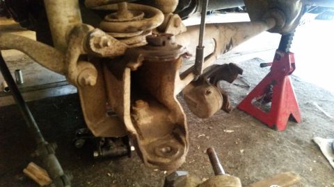 1985 Ford Bronco - This close-up view shows the suspension components of a vehicle, including a rusty ball joint assembly and a coil spring, supported by a re…