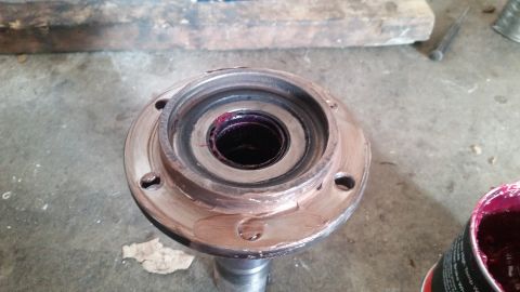 1985 Ford Bronco - A close-up view of a greased wheel bearing assembly, likely for a 1985 Ford Bronco, with a can of red grease visible in the lower right cor…