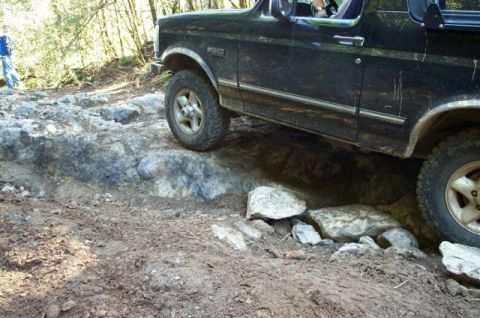 1995 Ford Bronco - A black 1995 Ford Bronco tackles a challenging rocky trail, demonstrating its off-road capabilities.