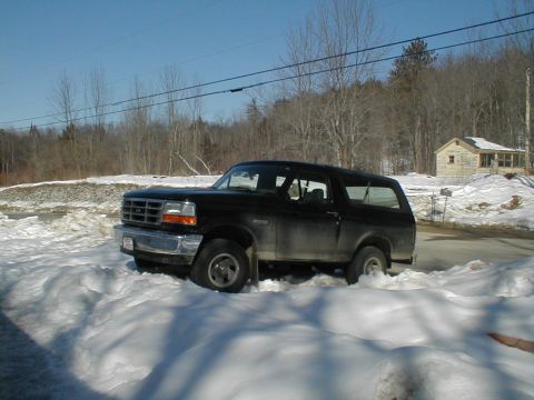 1994 Ford Bronco - Black 1994 Ford Bronco partially buried in snow drifts on a sunny day.