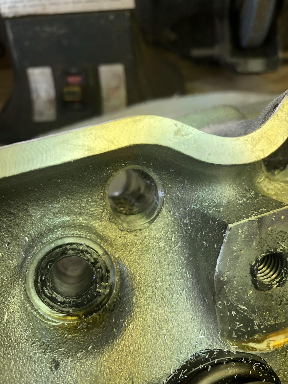 Machined metal part with circular openings and metal shavings.