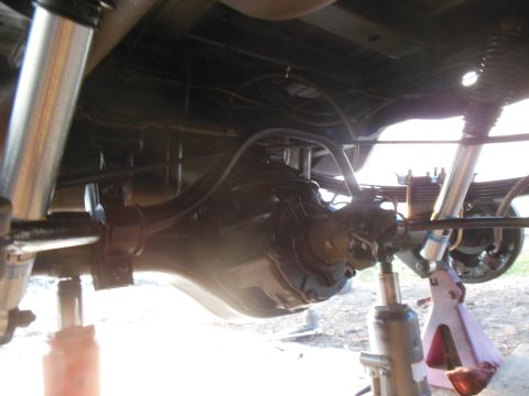 1984 Ford Bronco - The underside of a vehicle, likely a 1984 Ford Bronco, showing the rear differential, leaf springs, and shocks. The vehicle is supported by…