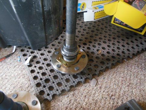 1984 Ford Bronco - A close-up view of a vehicle's axle hub assembly with a metal shaft extending upwards. The assembly is resting on a textured black mat plac…