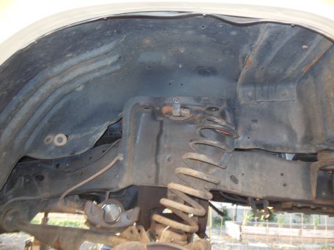 1984 Ford Bronco - This is a close-up view of the undercarriage of a vehicle, focusing on the suspension system. Visible components include a coil spring, par…