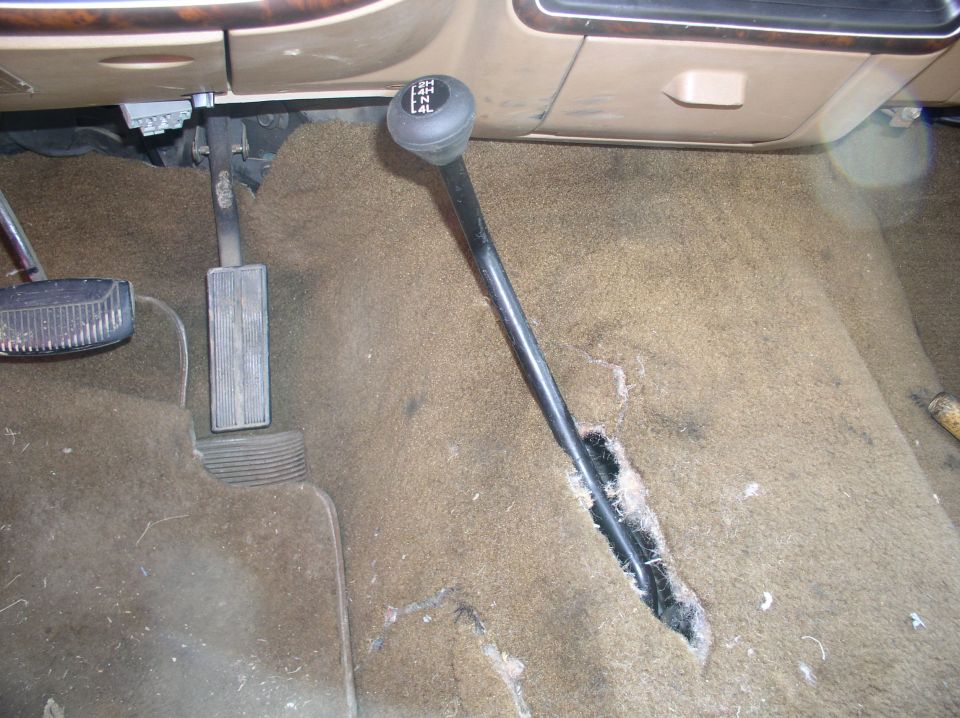 Transfer case shifter with 2H, 4H, 4L markings in a tan carpeted vehicle interior