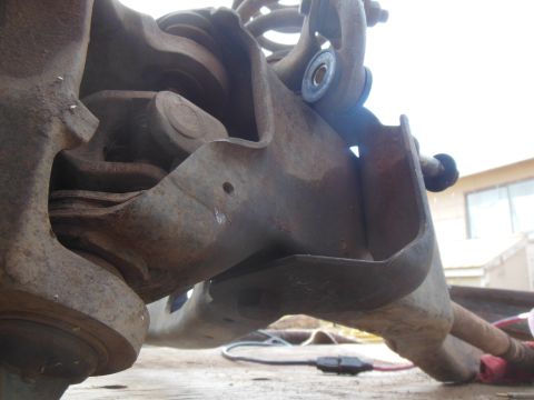 1984 Ford Bronco - A close-up, low-angle view of heavily rusted suspension components, likely from a 1984 Ford Bronco, showing a ball joint, control arm, and…