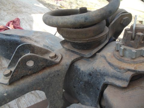 1984 Ford Bronco - A close-up view of rusted suspension components, including a coil spring and mounting brackets, on what appears to be an older vehicle.