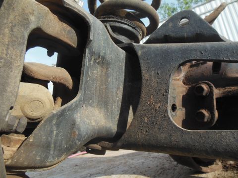 1984 Ford Bronco - A close-up view of heavily rusted, black-painted suspension components on a vehicle, possibly from a 1984 Ford Bronco. The image shows a co…