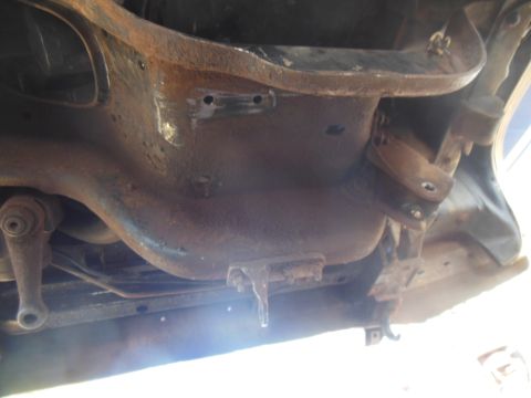 1984 Ford Bronco - This is an underside view of a heavily rusted vehicle frame, possibly from a 1984 Ford Bronco. Various metal components and suspension part…