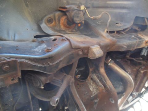 1984 Ford Bronco - This is a close-up, low-angle shot of heavily rusted and corroded automotive frame components, likely from the undercarriage of a vehicle.…