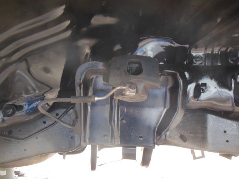 1984 Ford Bronco - A close-up view of the underside of a vehicle's suspension system, focusing on the brake caliper and brake line assembly. The components ar…