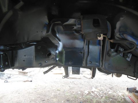 1984 Ford Bronco - The underside of a vehicle's frame and suspension components, painted black, are visible. A brake caliper and brake line are also visible a…