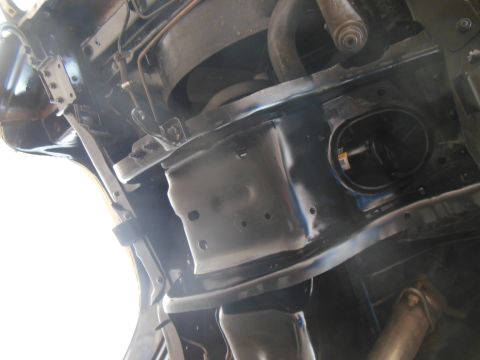 1984 Ford Bronco - Underside view of a black vehicle chassis, showing structural components, a black oil filter housing, and part of an exhaust pipe.