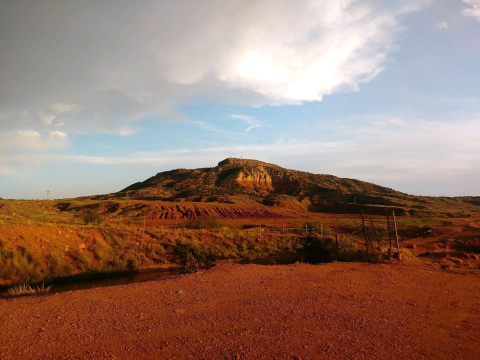 Arid landscape with mesa under a partly cloudy sky.