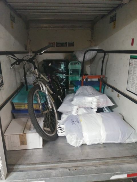 1996 Ford Bronco - A bicycle is loaded into the back of a cargo van or truck, along with several plastic-wrapped items and boxes. The bicycle is positioned up…
