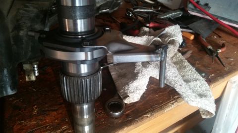 1985 Ford Bronco - A close-up view of a vehicle's transmission input shaft and clutch release bearing assembly on a wooden workbench. Tools and a rag are visi…