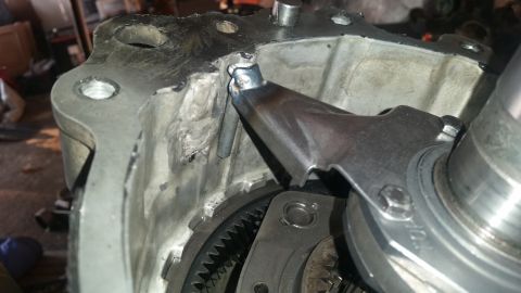 1985 Ford Bronco - Close-up view of a modified metal component, possibly a transmission or transfer case housing, with visible welding and a metal lever mecha…