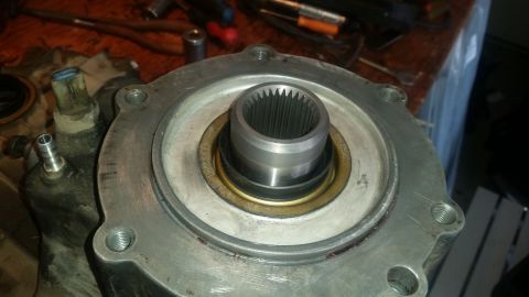 1985 Ford Bronco - A close-up view shows the splined input shaft of a transfer case, surrounded by a metal housing with several bolt holes. A brass-colored se…