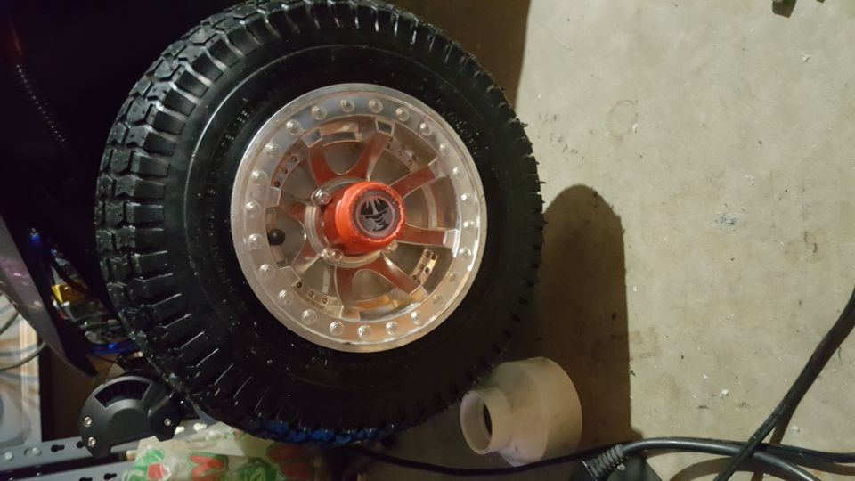 Close-up of a rugged tire and silver rim with red accents on a concrete floor.
