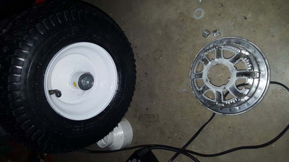 Tire and wheel assembly next to a silver disc with a black cable.