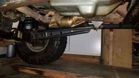 1996 Ford Bronco - Underside view of a modified vehicle's rear suspension and drivetrain components, including a large tire and exhaust system. The vehicle ap…