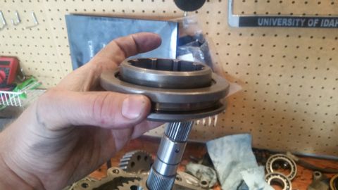 1985 Ford Bronco - A person's hand holds a metal automotive part, likely a synchronizer ring and collar assembly, with splines visible on the shaft below. The…