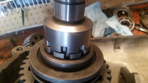 1985 Ford Bronco - A close-up view of a metal shaft with splines and a collar assembly, possibly part of a transmission or transfer case, with gears visible i…