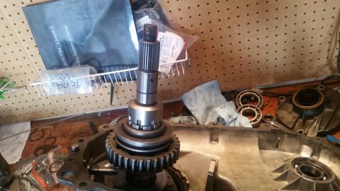 1985 Ford Bronco - A close-up view of a transmission component with gears and a splined shaft, likely part of a Ford Bronco's drivetrain. Various bearings and…