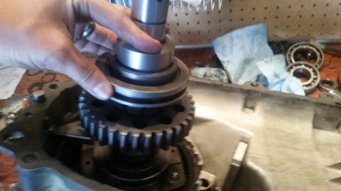 1985 Ford Bronco - A person's hands are shown assembling a transmission or transfer case component. A large gear is visible within the housing, and a cylindri…