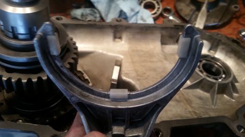 1985 Ford Bronco - A close-up shot shows a U-shaped metal part with white plastic inserts, held by a hand. The part is positioned over a disassembled mechanic…