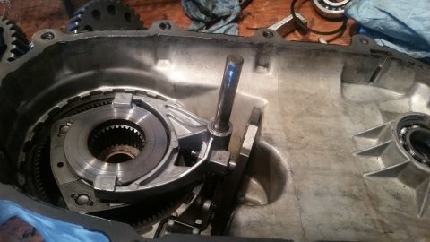 1985 Ford Bronco - The interior of a transmission case is shown, with gears and a shift mechanism visible. A metal rod extends upwards from the mechanism.