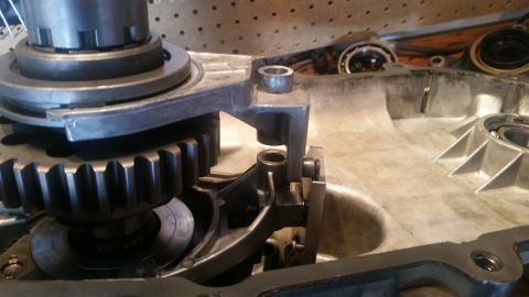 1985 Ford Bronco - A close-up view of internal transmission components, including gears and a shift fork mechanism, within a silver-colored transmission housi…