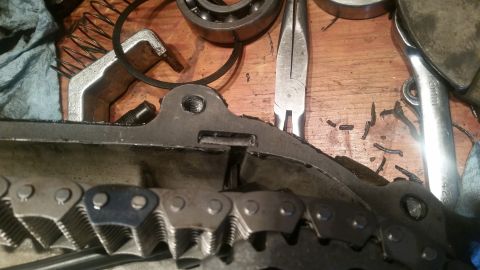 1985 Ford Bronco - A close-up view of a timing chain and related engine components on a wooden workbench. Tools like pliers and a wrench are visible in the ba…