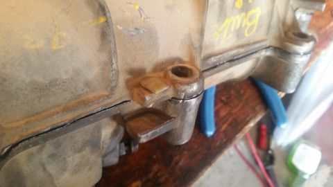 1985 Ford Bronco - A close-up view shows a cracked gasket seal on a heavily used, tan-colored metal housing, possibly a transmission or transfer case. Yellow…
