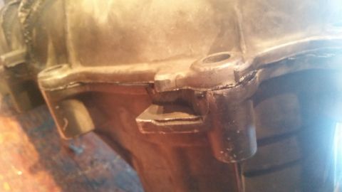 1985 Ford Bronco - A close-up view of a damaged gasket seal on a metal automotive part, possibly part of a transmission or engine casing. The gasket appears t…