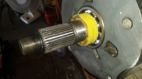 1985 Ford Bronco - A close-up view shows a splined shaft with a threaded end, a yellow plastic spacer, and a bearing assembly attached to a metal component. T…
