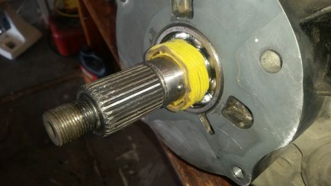 1985 Ford Bronco - A close-up view of a splined shaft with a yellow plastic spacer around a bearing, attached to a metal housing.