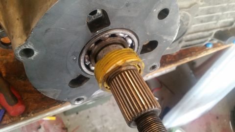 1985 Ford Bronco - A close-up view shows a splined shaft protruding through a bearing and a metal plate. The shaft has a yellow protective wrap around its upp…