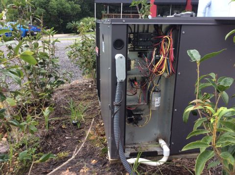 1992 Ford Bronco - The image shows the open access panel of an outdoor air conditioning unit, revealing its internal wiring, capacitors, and electrical compon…